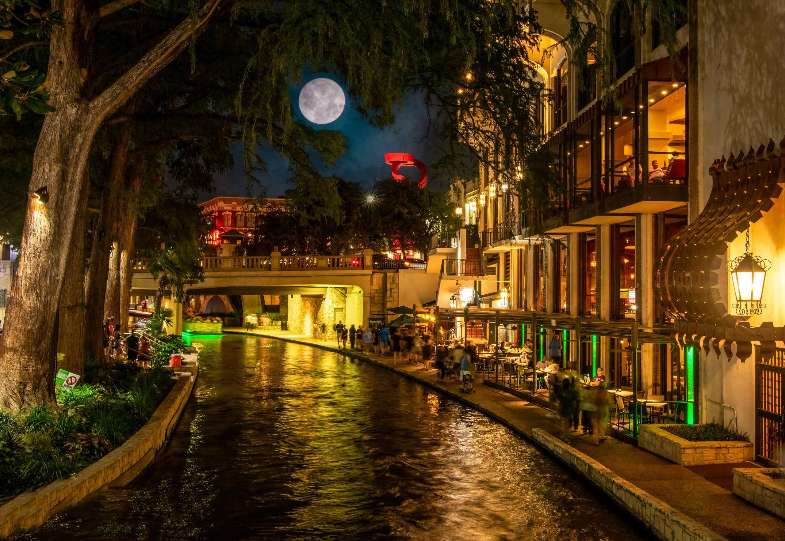 San Antonio River Walk at night with illuminated restaurants, historic architecture and riverside walkways